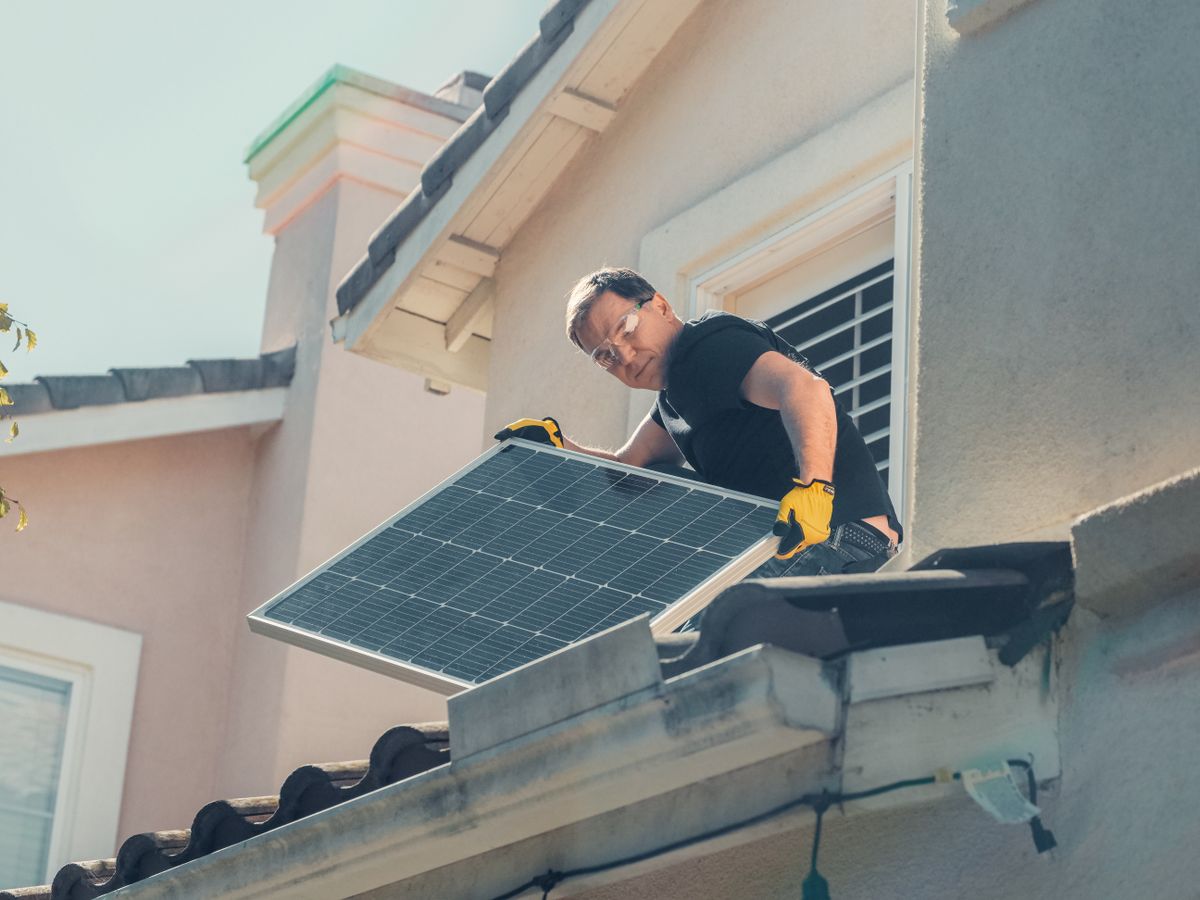 An installer fixing a solar panel into place on a roof