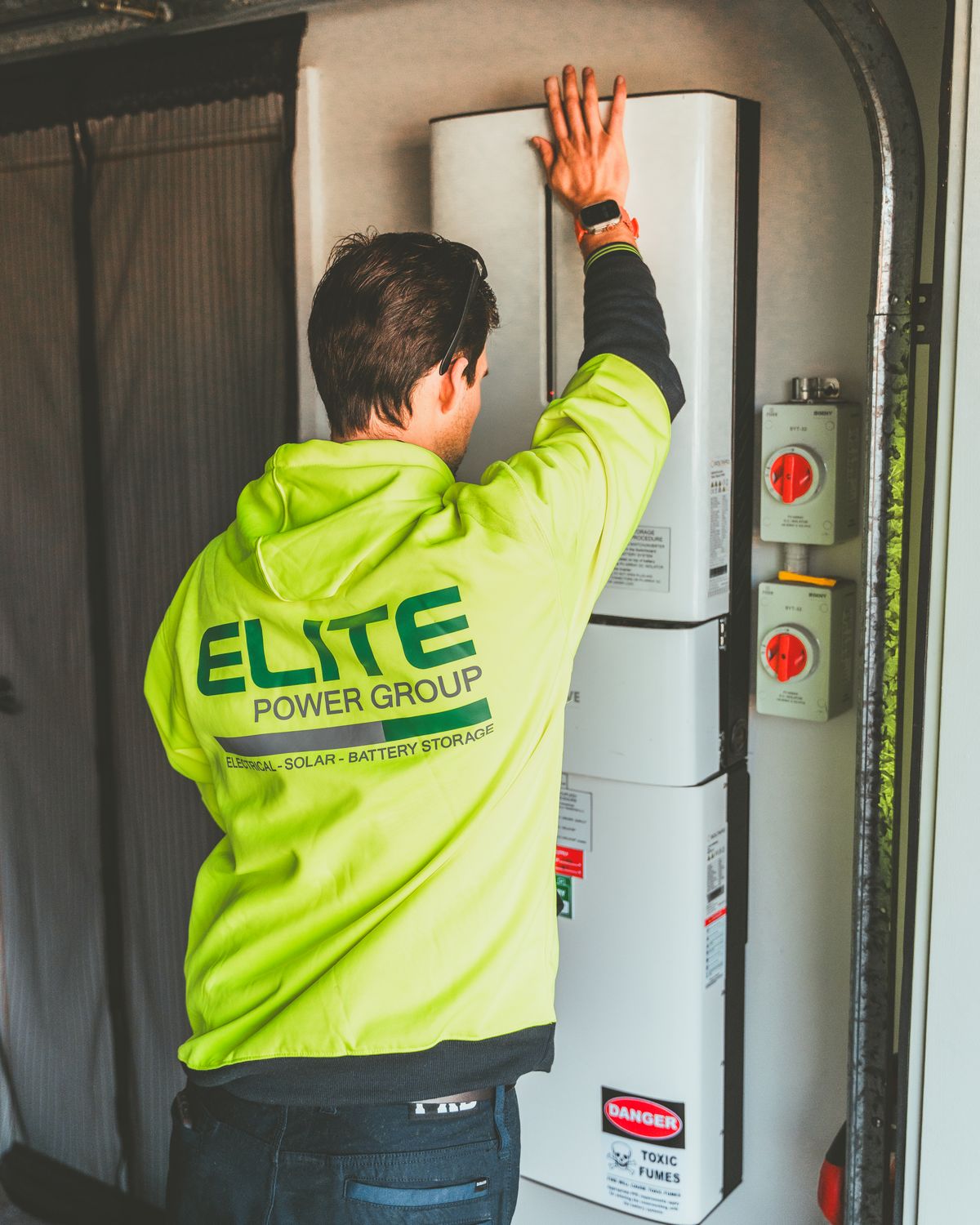 A technician installing an inverter and battery system on a wall