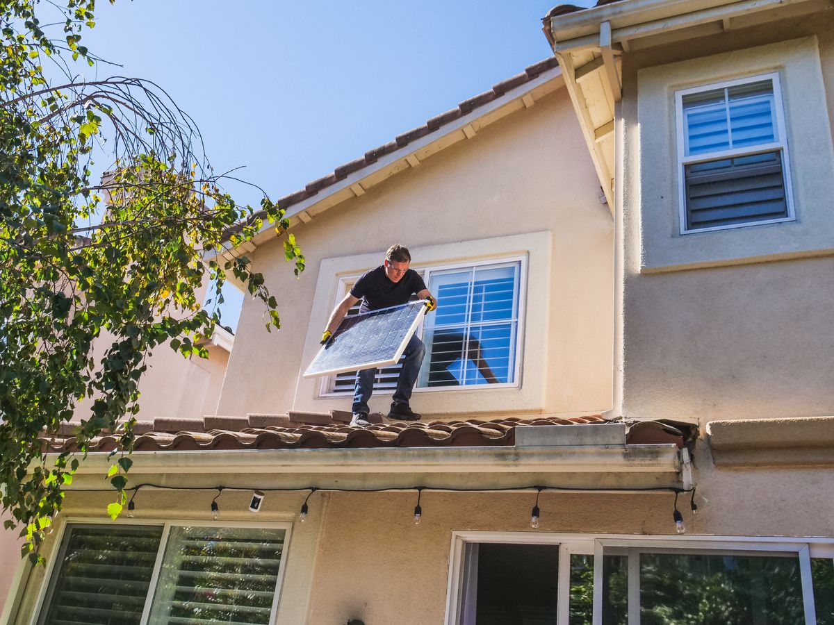 Solar technician fitting panels on a house roof