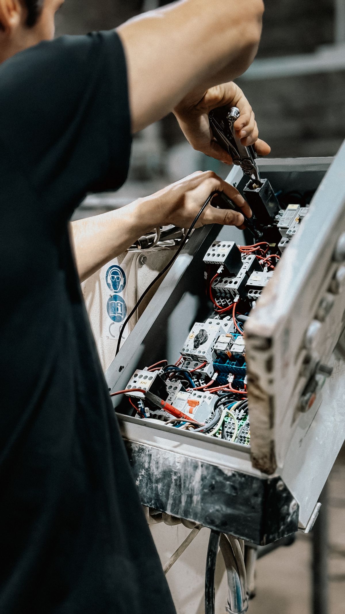 Technician adjusting wires inside a control panel