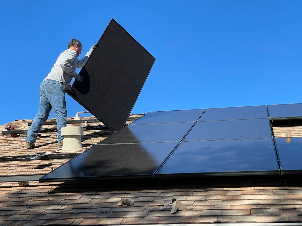 Worker installing solar panels in bright sun