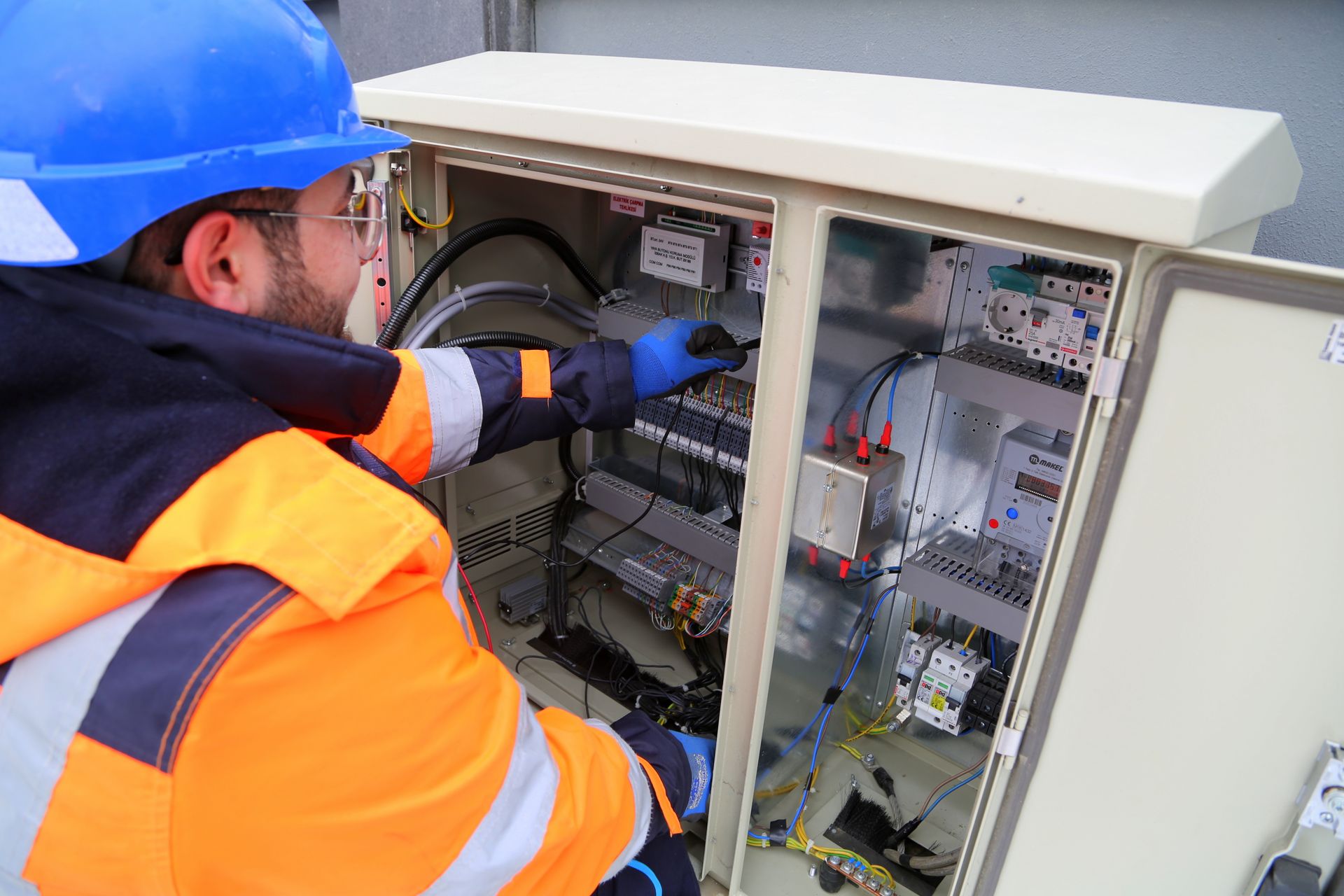 An electrician working on an outdoor electrical panel