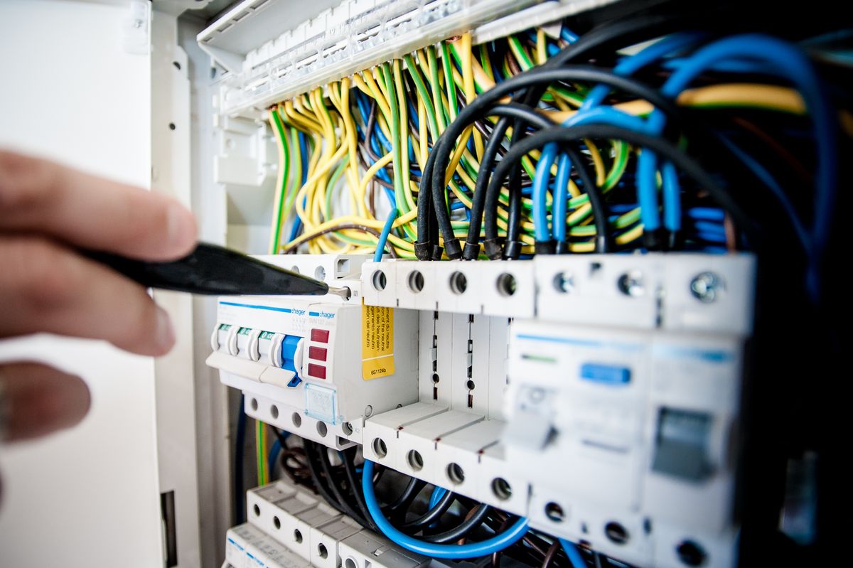 An electrician working inside a circuit breaker panel
