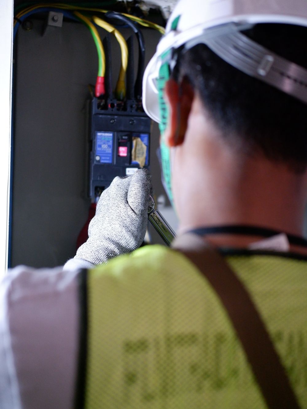 Electrician working on a circuit breaker wearing safety gloves