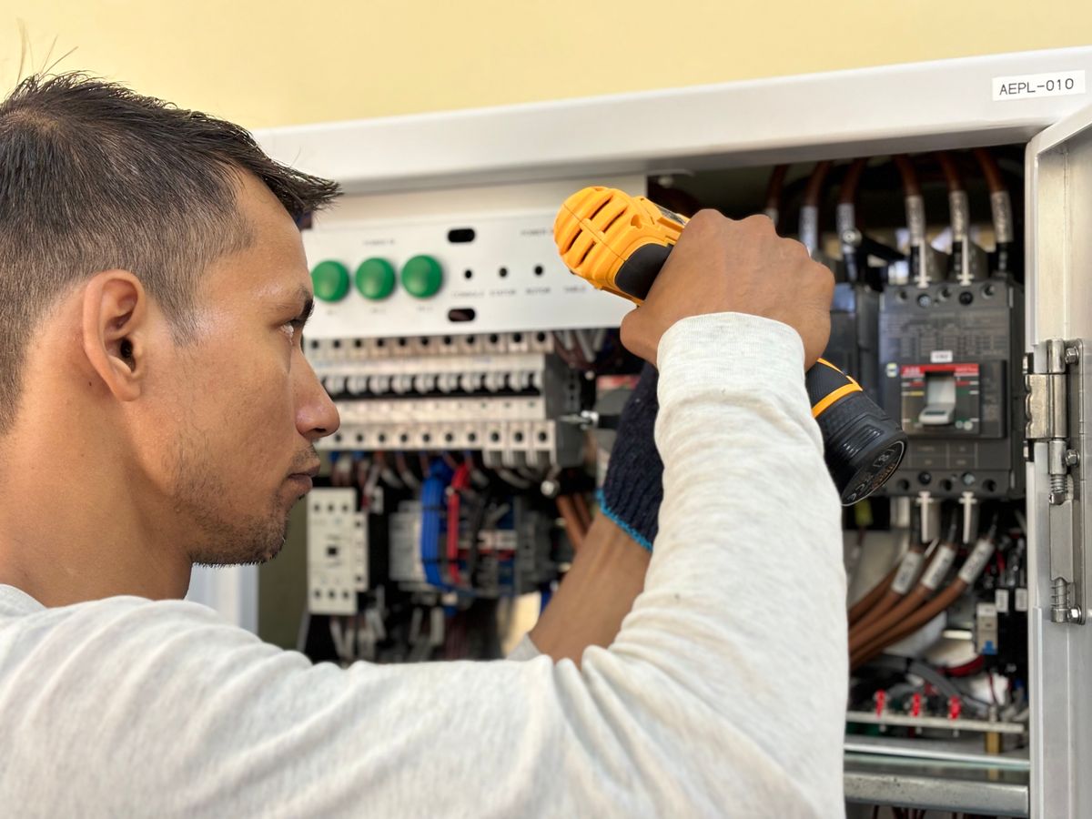 Electrician fitting equipment into a commercial breaker board
