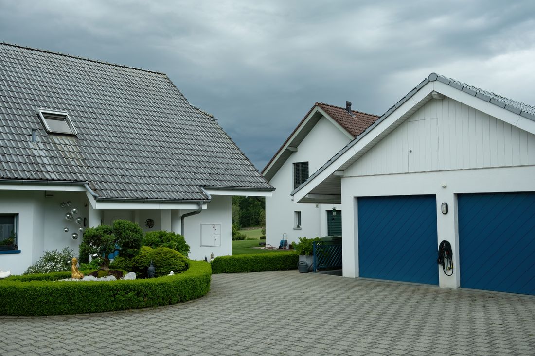 A paved driveway running up to a house with painted walls and garage doors