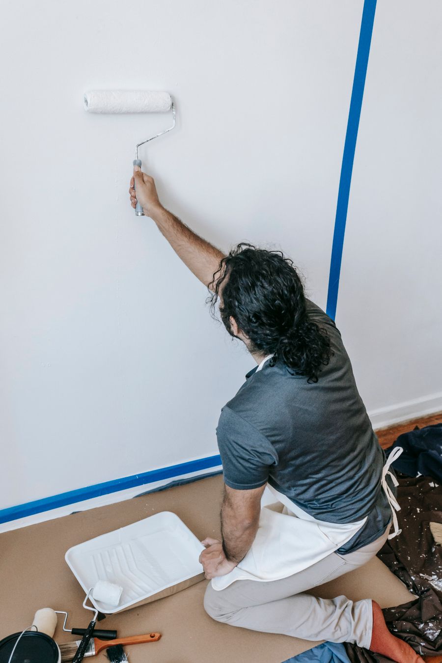 A painter rolling a fresh coat onto an interior wall, edges masked off