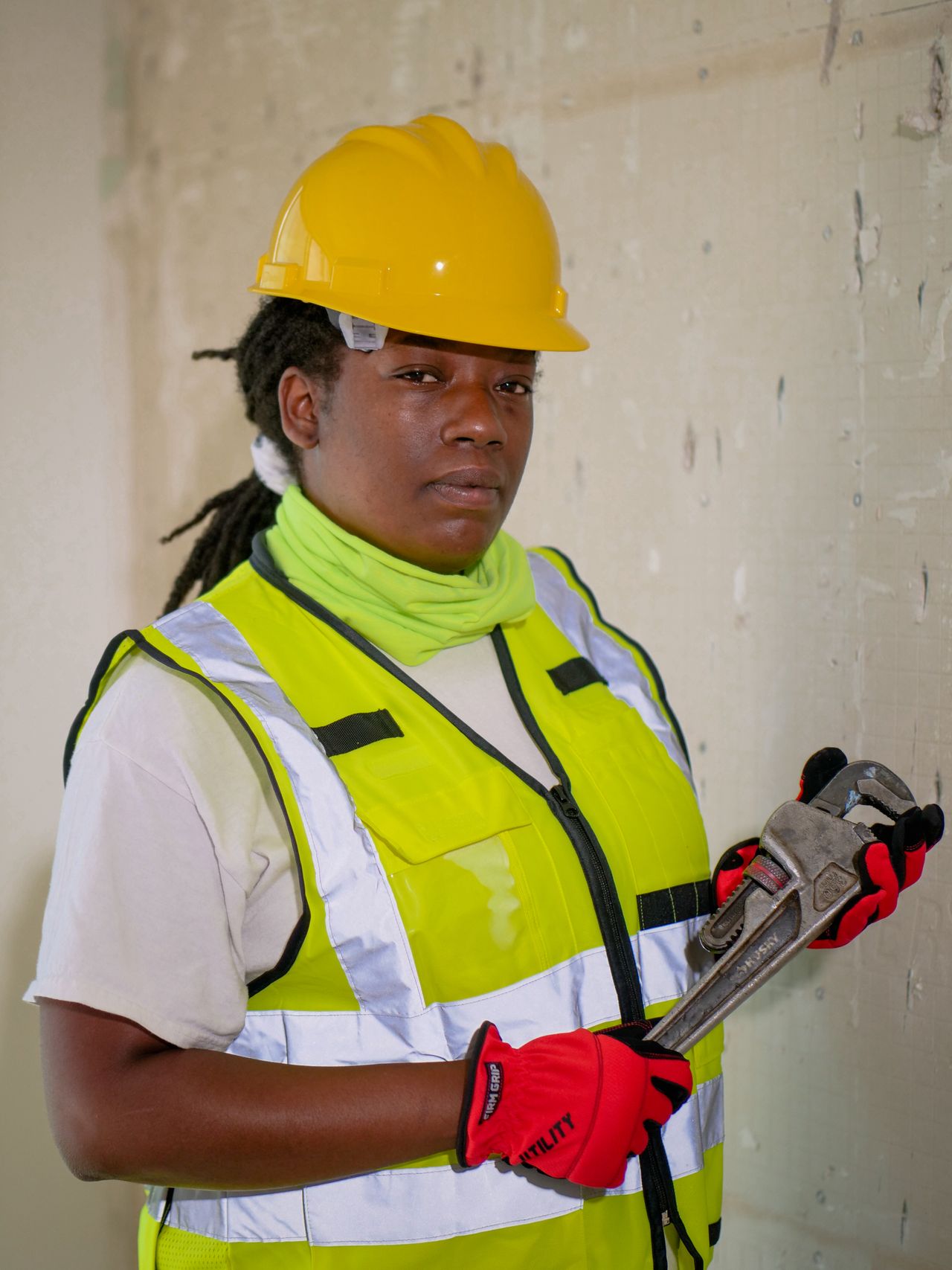 Registered plumber in safety gear holding a pipe wrench