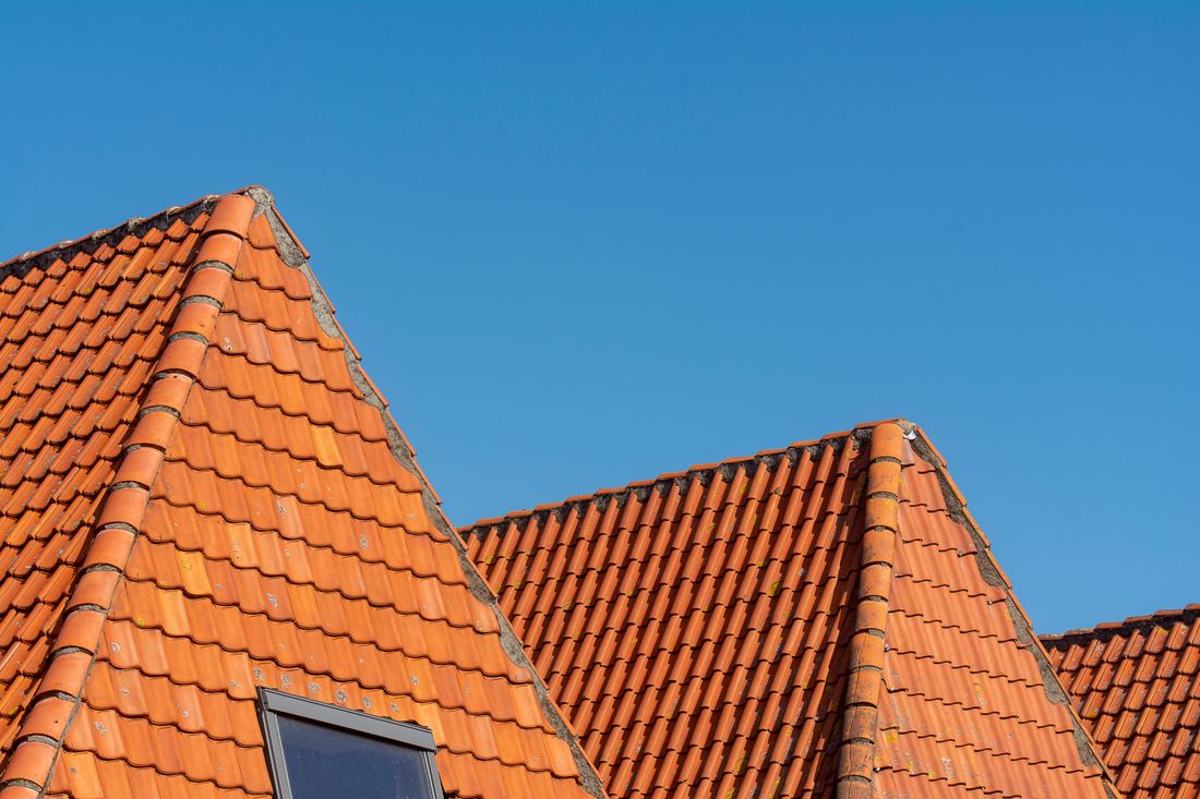 Clean red roof tiles in sharp condition against a clear blue sky