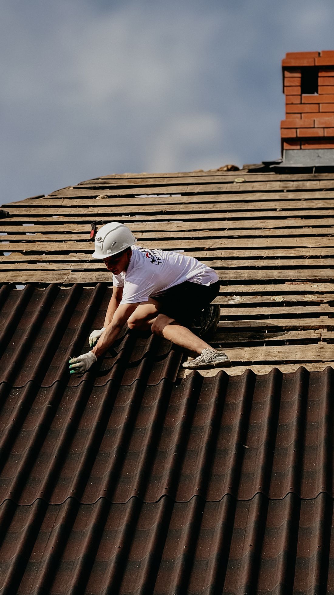 A roofer harnessed and working on a roof slope in safety gear