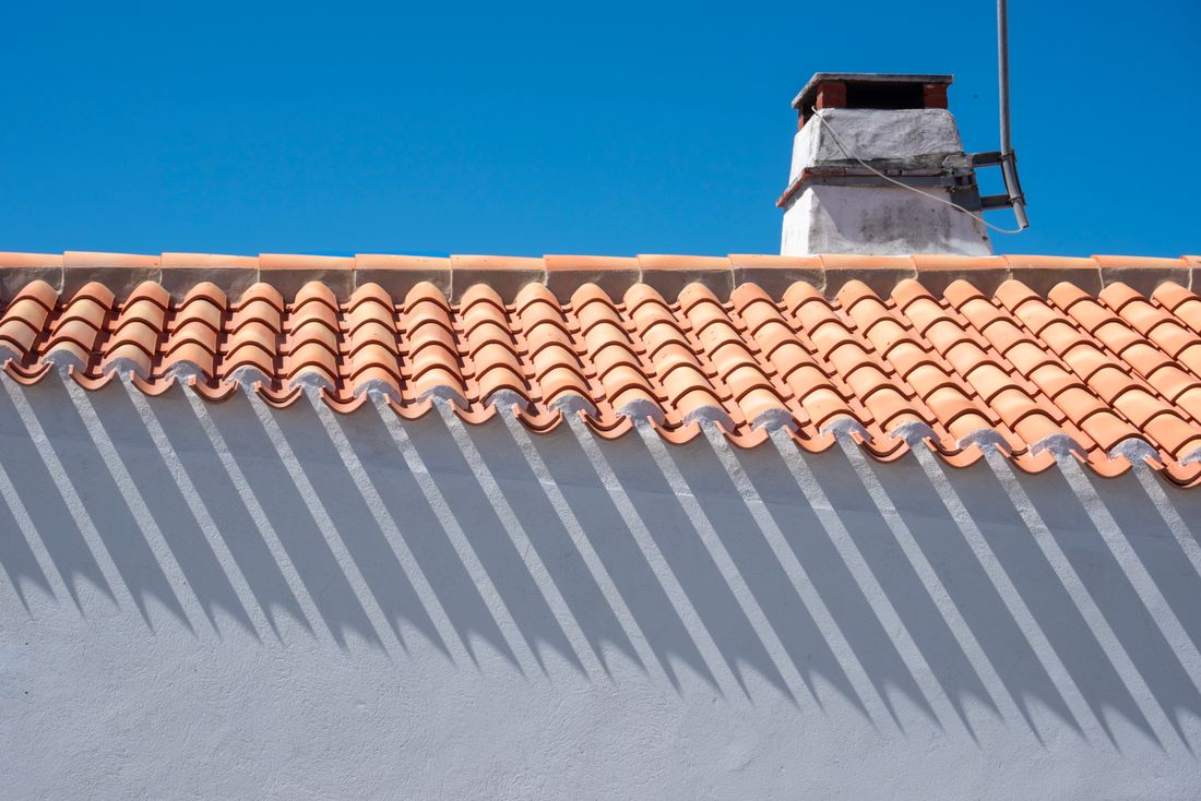 Textured roof tiles and a chimney stack under clear sky